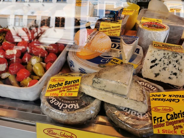 Günzburger Wochenmarkt Eine reizvolle Käseauslage auf einem Markt zeigt verschiedene Käsesorten, die liebevoll drapiert sind.