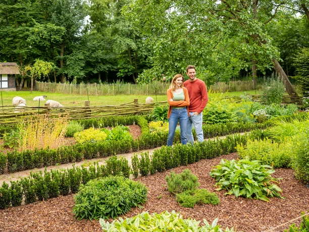 Rahden-Museumshof-Teutoburger-Wald-Tourismus-D-Ketz-018.jpg Ein lächelndes Paar spaziert durch einen gepflegten, grünen Garten mit umgebenden Bäumen.
