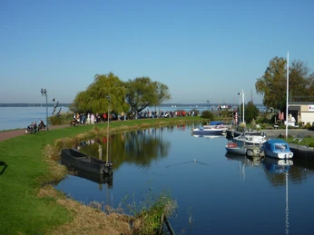 Promenade Steinhude mit Hafen Boote im Hafen von Steinhude, mit ruhigem Wasser und Menschen, die die Promenade entlangspazieren.