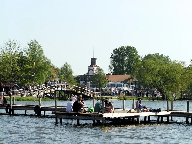 Promenade mit Steg Menschen genießen an einem sonnigen Tag den Blick auf den See von einem hölzernen Steg und Umgebung.