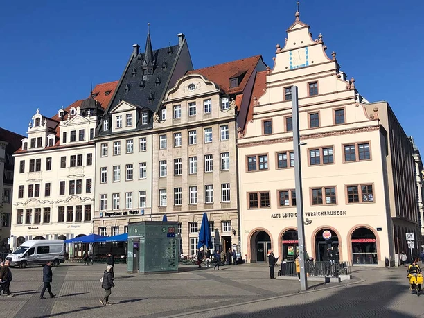 Stare wagi na rynku w centrum Lipska Stare wagi w centrum Lipska z przechodniami w promieniach słońca