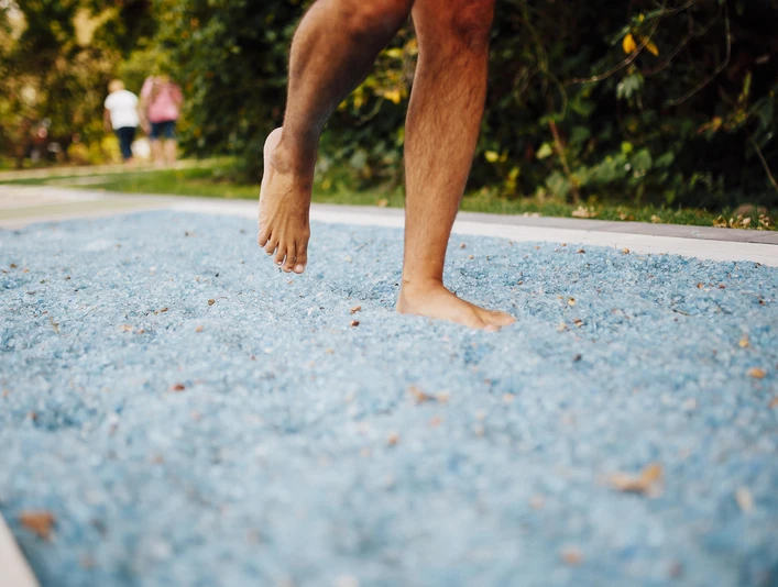 Barfußpfad Mann geht über blaue Steine