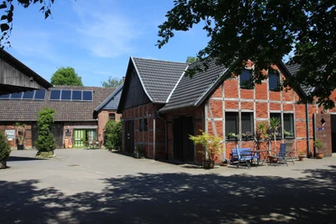 Ferienwohnung-Bergmann-Scholvien.jpg Ferienwohnung in einem historischen Fachwerkhaus mit Innenhof, umgeben von Bäumen und Gartenmöbeln.