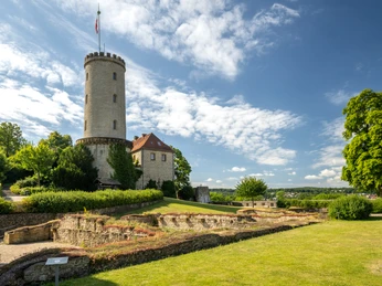 Bielefeld-Sparrenburg-Teutoburger-Wald-Tourismus-D-Ketz-040-2.jpg <p>Der Burgturm ragt majestätisch über historische Ruinen in einer grünen Parklandschaft empor.</p>