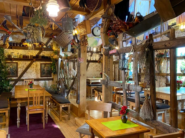 Cozy, rustic dining room with wooden furniture, decorations such as baskets and dried flowers, warm lighting and an inviting atmosphere.