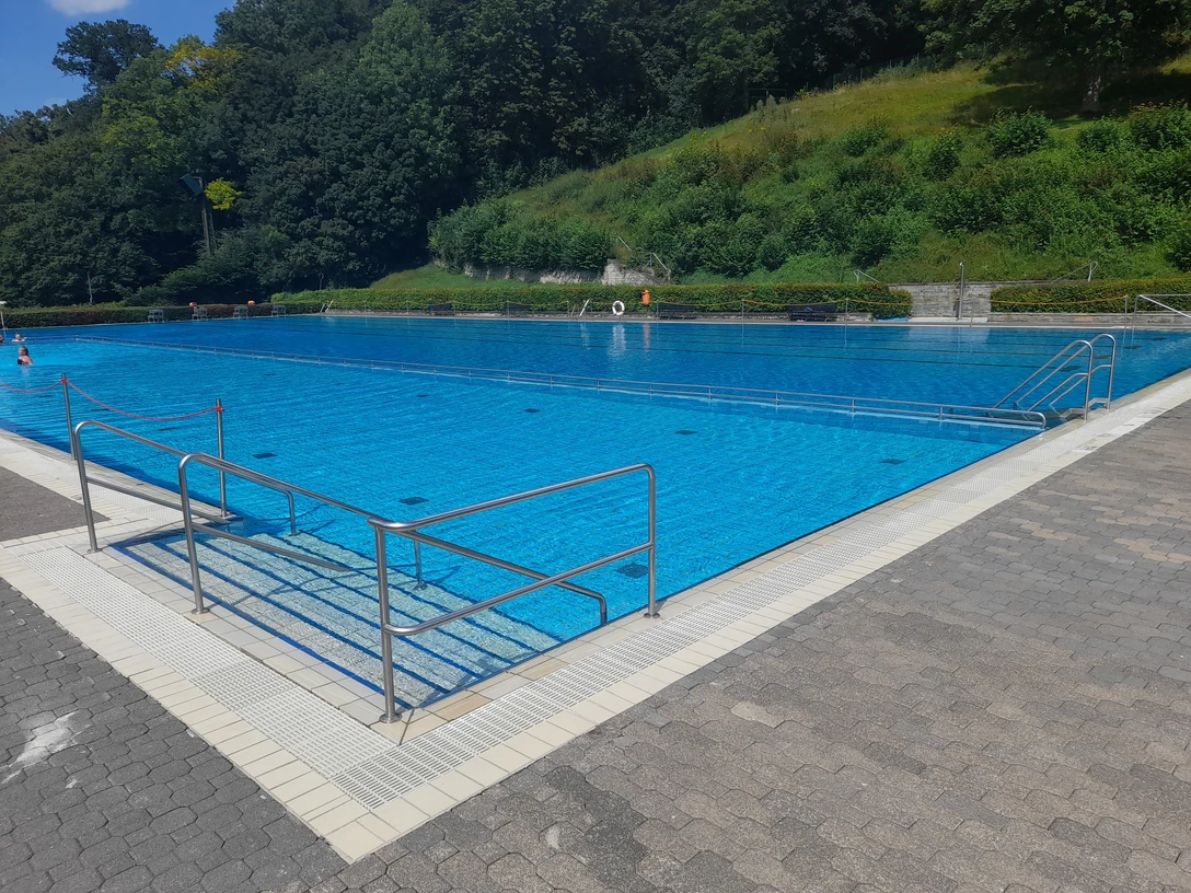 Freibad Büren Freibad Büren: Modernes Schwimmbecken umgeben von Grüngürtel und Zugangstreppe am Beckenrand.