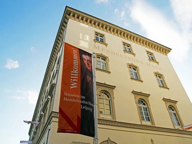 Facade of the Mendelssohn House in Leipzig with blue sky and banner.