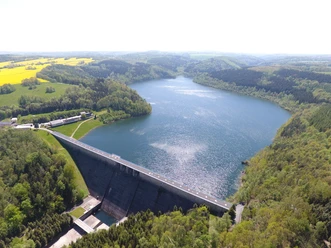 Talsperre Gottleuba Stausee mit umliegenden Wäldern und Feldern. Im Vordergrund eine beeindruckende Staumauer.