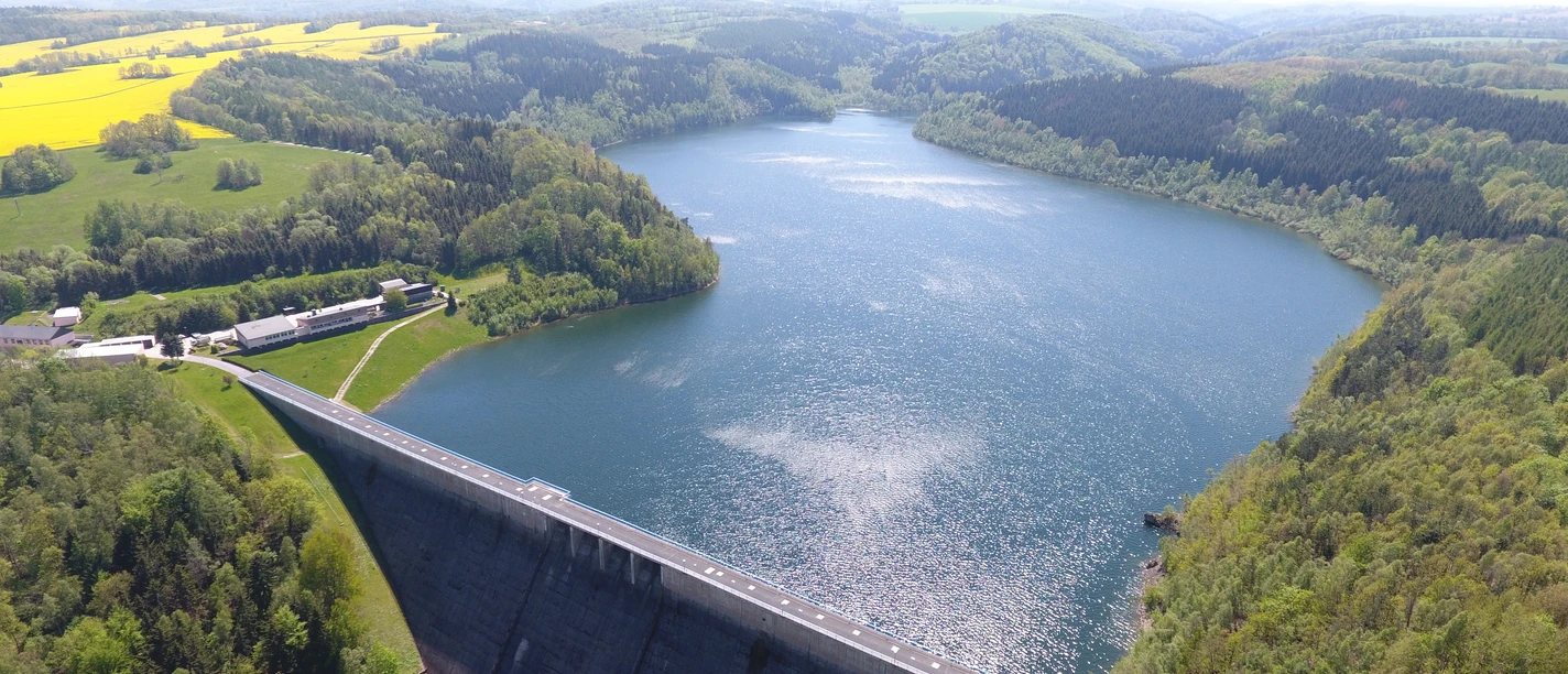 Talsperre Gottleuba Stausee mit umliegenden Wäldern und Feldern. Im Vordergrund eine beeindruckende Staumauer.