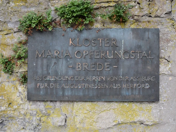 Gedenktafel aus Metall mit der Inschrift "Kloster Maria Opferungsstal - Brede" an einer alten Steinwand.