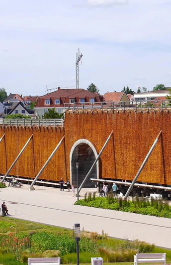 Gradierwerk zur Sole-Inhalation, flankiert von Bäumen, mit Menschen entlang der Außenfläche.