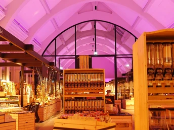 Innenansicht der Herford Markthalle mit beleuchtetem Tonnengewölbe und hölzernen Produktregalen.