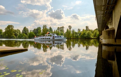 Weiße Flotte, Mülheim an der Ruhr Schiff der Weißen Flotte auf der Ruhr, umgeben von grünen Bäumen und einer Brücke rechts im Bild.