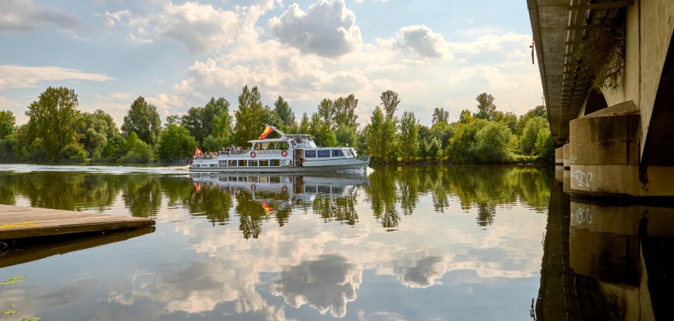 Weiße Flotte, Mülheim an der Ruhr Schiff der Weißen Flotte auf der Ruhr, umgeben von grünen Bäumen und einer Brücke rechts im Bild.