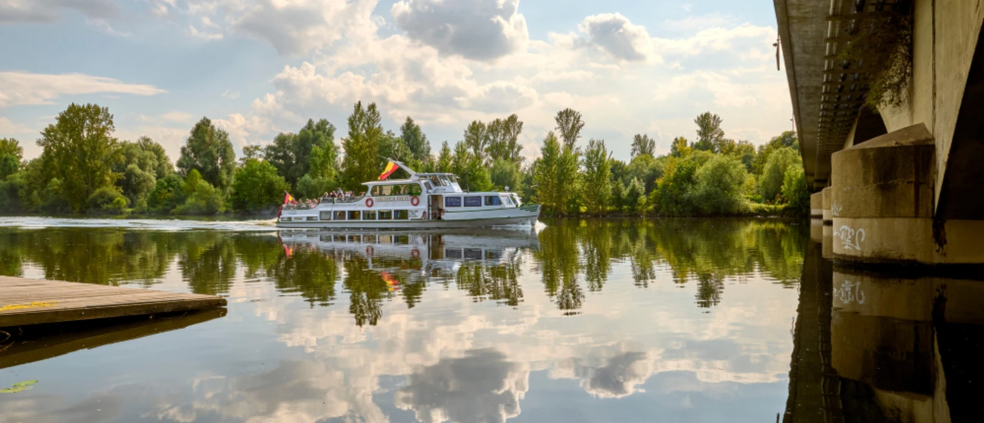 Weiße Flotte, Mülheim an der Ruhr Schiff der Weißen Flotte auf der Ruhr, umgeben von grünen Bäumen und einer Brücke rechts im Bild.
