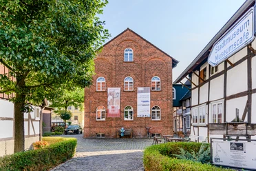 Historisches Backsteingebäude des Stadtmuseums Lemgo, flankiert von Fachwerkhäusern und einem Baum.