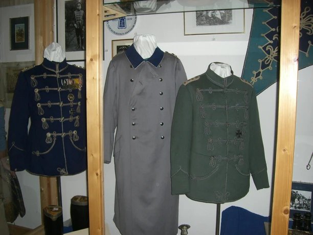CIMG5700.JPG Historische Uniformen und Mäntel im Raum ausgestellt, mit Fotos und Dekorationen an den Wänden.