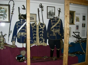 Historische Uniformen und Waffen in einem Ausstellungsraum, in Vitrinen präsentiert.