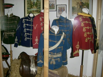 Historische Militäruniformen in leuchtenden Farben ausgestellt in einem kleinen Museum auf Stroh gebettet.