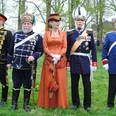 Eine Gruppe von Personen in historischen Militäruniformen steht nebeneinander auf einer Wiese.