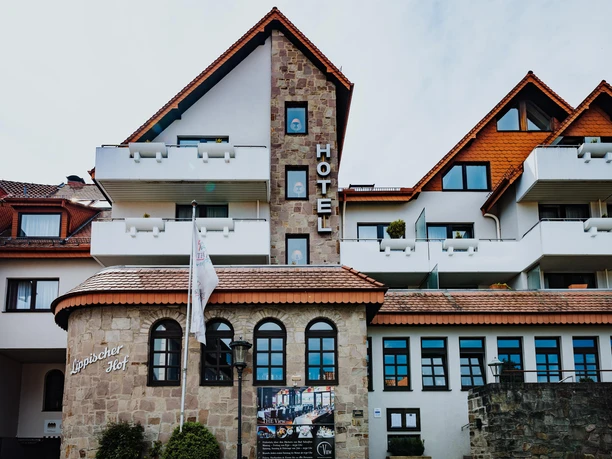Außenansicht des Hotels Lippischer Hof mit Natursteinfassade, roten Dächern und Balkonen