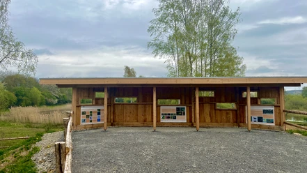 Ein hölzerner Unterstand mit Infotafeln bietet Ausblick auf die Natur und renaturierte Tongruben.