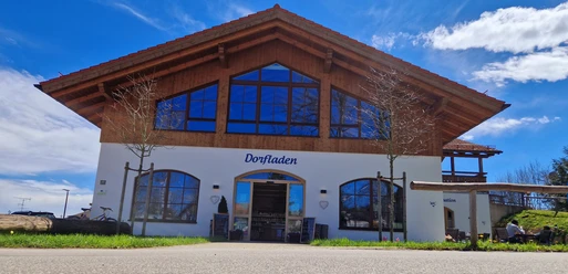 Dorfladen Grafenaschau Dorfladen Grafenaschau, weißes Gebäude mit Holzverkleidung und blauem Schriftzug.