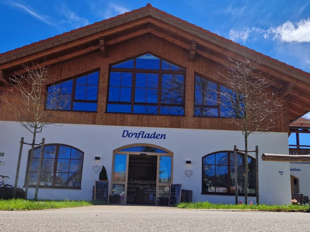 Dorfladen Grafenaschau Dorfladen Grafenaschau, weißes Gebäude mit Holzverkleidung und blauem Schriftzug.