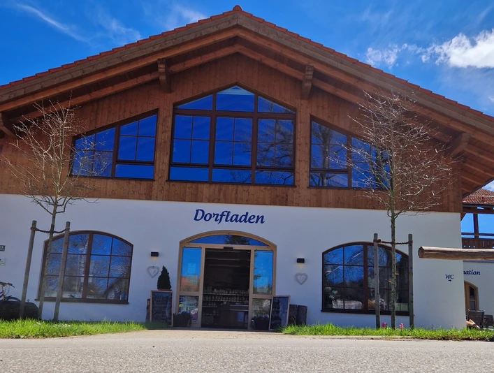 Dorfladen Grafenaschau Dorfladen Grafenaschau, weißes Gebäude mit Holzverkleidung und blauem Schriftzug.