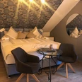 Pension © Ottenheide (1).jpeg Dreibettzimmer mit Doppelbett, gemütlichen Kissen, zwei Stühlen und einem kleinen runden Tisch.