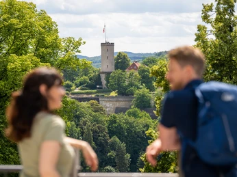 Bielefeld-Johannisberg-Teutoburger-Wald-Tourismus-D-Ketz-049.jpg Zwei Menschen betrachten eine Burgruine im Grünen; im Hintergrund sieht man einen Burgturm.