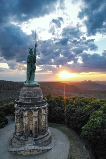 Hermannsdenkmal-Detmold-Teutoburger-Wald-Tourismus-D-Ketz-111-CC-BY-SA.jpg Das Hermannsdenkmal ragt monumental im Teutoburger Wald in der Abenddämmerung unter dramatischen Wolken auf.