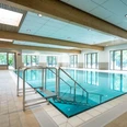 Sielbad Bad Oeynhausen Lichtdurchflutetes Hallenbad mit großen Fenstern, modernem Edelstahlbecken und breiter Einstiegstreppe.