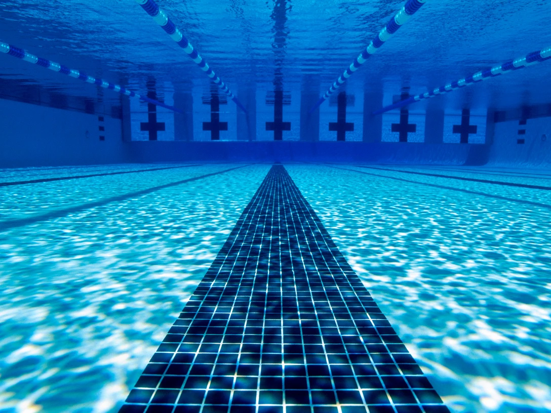 Freibad Ein leeres Schwimmbecken zeigt klare Bahnen und reflektiertes Licht am Beckenboden durch klares Wasser.