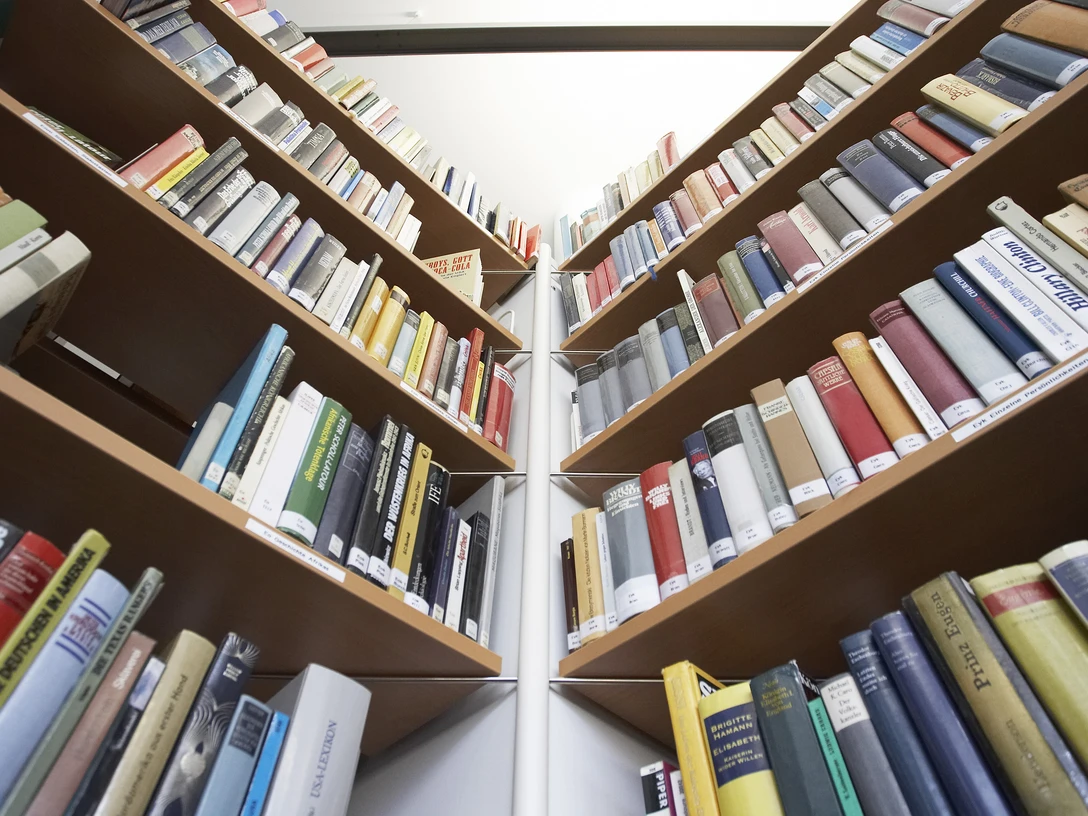 Stadtbücherei Bad Oeynhausen Zwei Reihen von Bücherregalen voller farbiger Bücher, fotografiert aus einem niedrigen Blickwinkel.