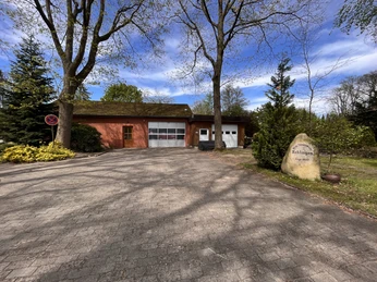 Freiwillige Feuerwehr Rehlingen Backsteinbau der Freiwilligen Feuerwehr Rehlingen mit breiter Einfahrt und Gedenkstein im Grünen.
