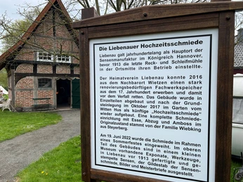 Hochzeitsschmiede Schild vor dem historischen Gebäude "Liebenauer Hochzeitsschmiede" mit ausführlichem Erklärungstext.