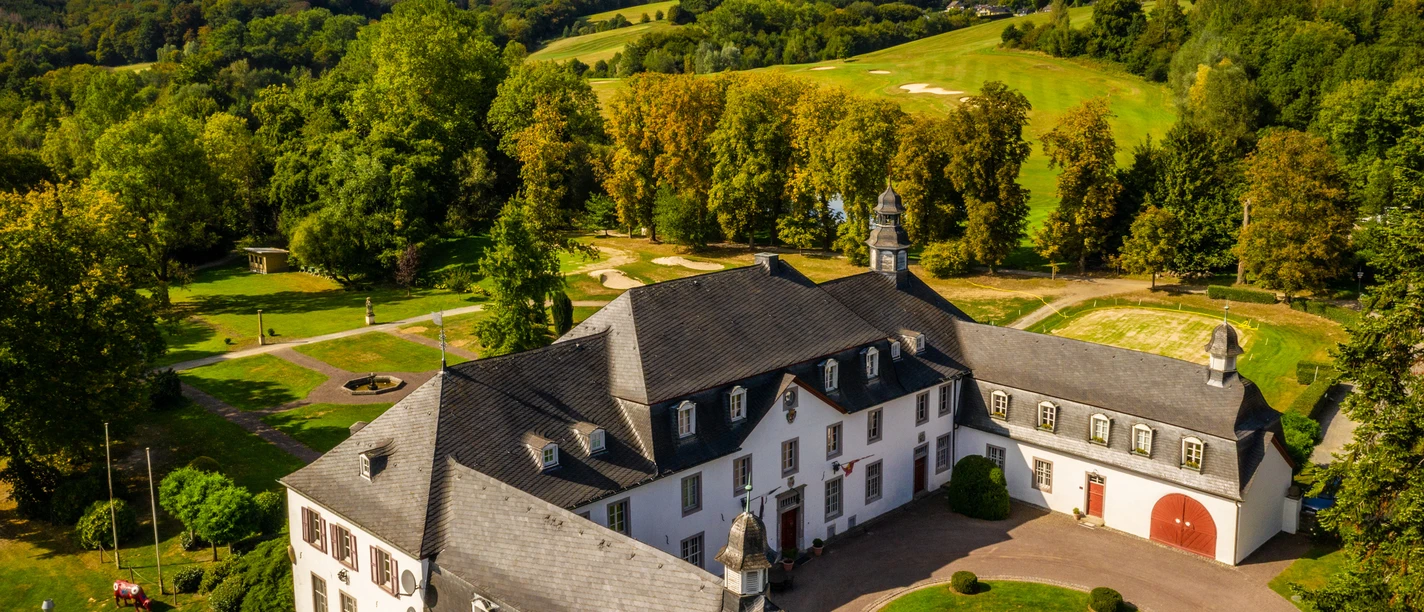 Schloss Auel Schloss Auel, barockes Herrenhaus inmitten grüner Landschaft mit gepflegtem Garten und Bäumen.