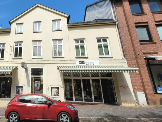 Buchhandlung Weber_Silvana Dust_20230510 (4).jpg Die Vorderseite der Buchhandlung Weber. Ein helles Gebäude mit Parkmöglichkeiten davor