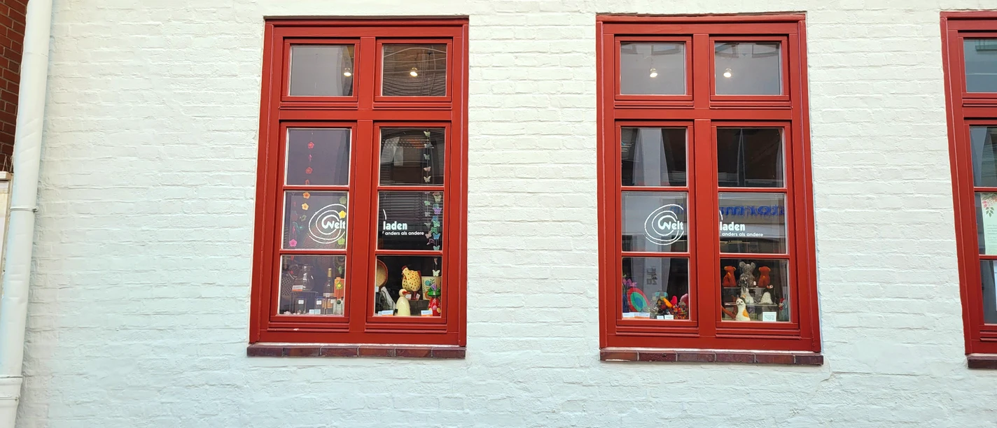 Weltladen Esperanza_Silvana Dust_20230510 (3).jpg Vom Gebäude sind zwei rote Fenster mit dem Aufdruck ‚Weltladen‘ zu sehen