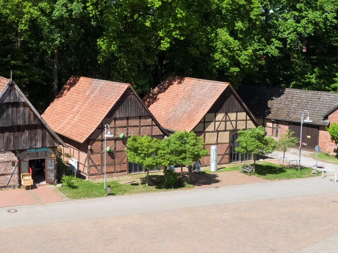 Infozentrum Steinhude_Claus Kirsch und Christian Stahl.jpg Fachwerkgebäude des Infozentrums Steinhude vor grünen Bäumen, mit rotem Ziegeldach und gepflastertem Platz.