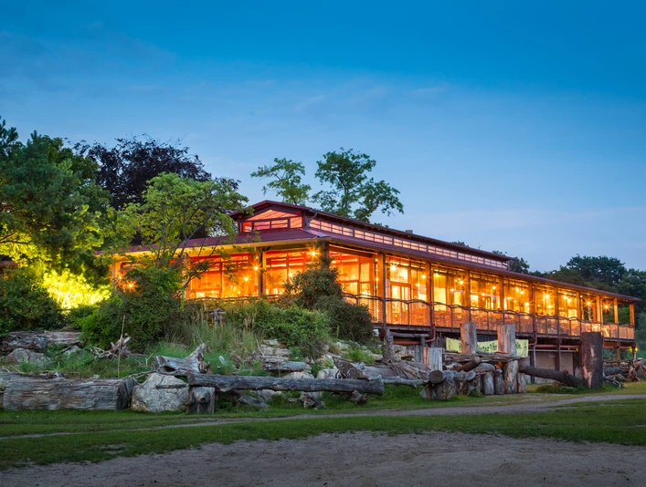 Event venue Kiwara Lodge at Leipzig Zoo | Leipzig Convention Bureau Außenaufnahme der Eventlocation Kiwara Lodge im Zoo Leipzig bei Nacht – präsentiert vom Leipzig Convention BureauNight-time exterior view of the event venue Kiwara Lodge at Leipzig Zoo – presented by Leipzig Convention Bureau