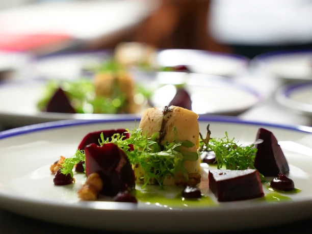 Bergische Genusstage Vorspeisenteller mit Roter Bete, Salat, Käse und Nüssen auf weißem Porzellanteller angerichtet.