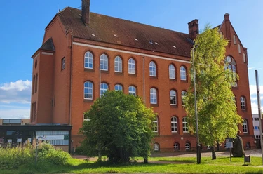 Volkshochschule_Silvana Dust_20230510_1980x1310.jpg Außenansicht der Volkshochschule Ratzeburg mit Eingangsbereich, Fenstern und umliegendem Gehweg sichtbar