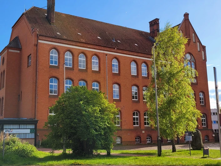 Volkshochschule_Silvana Dust_20230510_1980x1310.jpg Außenansicht der Volkshochschule Ratzeburg mit Eingangsbereich, Fenstern und umliegendem Gehweg sichtbar