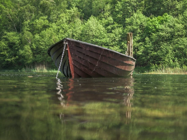 Ein altes Holz-Boot spiegelt sich im Wasser des Garrensees.