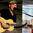 Sommer Konzerte Greetsiel: Oliver Jüchems Musiker spielt lächelnd Gitarre und singt bei einem Sommerkonzert in Greetsiel auf einer Open-Air-Bühne.
