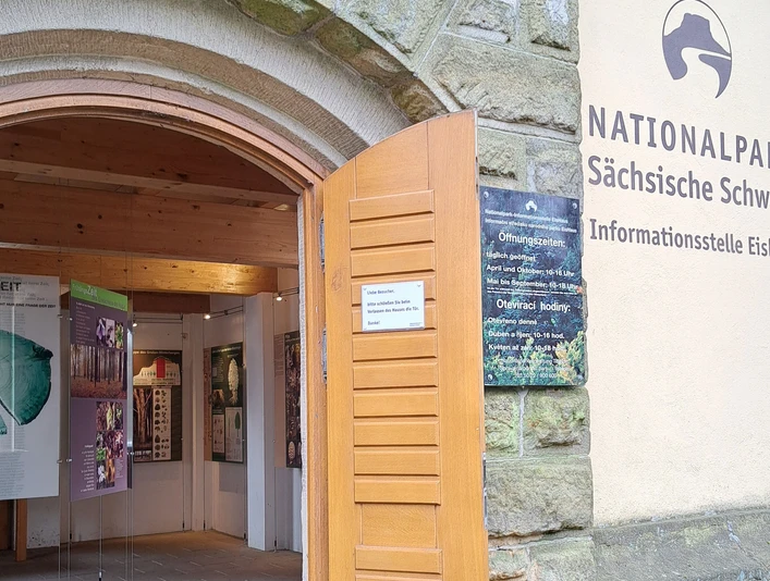 Eingang zur Infostelle Eishaus Eingang zur Informationsstelle Eishaus im Nationalpark Sächsische Schweiz mit offenen Holztüren und Infotafeln im Inneren.
