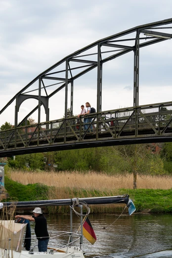 Zwei Menschen stehen auf einer Brücke. Sie schauen auf ein vorbeifahrendes Boot auf dem Elbe-Lübeck-Kanal.