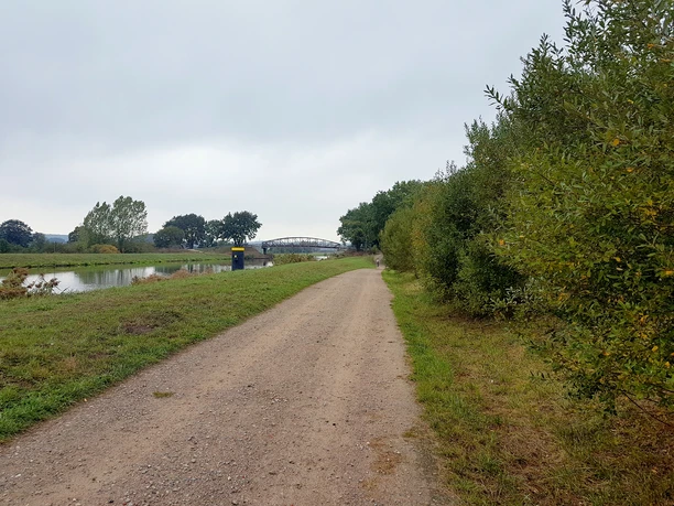 Ein Weg führt am Wasser entlang. Auf dem Weg kann man spazieren gehen oder Rad fahren.